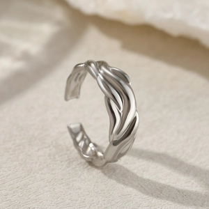 Macro shot of silver open ring with twisted wave texture and high-gloss metallic finish