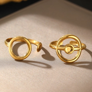 Detail of adjustable gold geometric rings with hollow design on textured surface