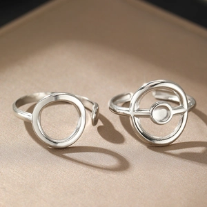 Detail of two minimalist silver adjustable open rings with hollow geometric patterns