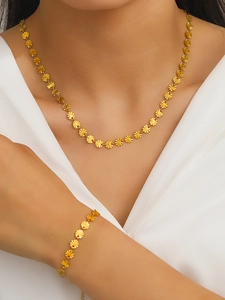 Detail of model wearing golden sunburst disk necklace and bracelet set on silk fabric