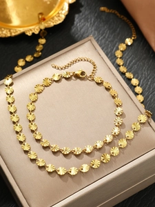 Detailed macro view of 18K gold-plated sunburst embossed round disc necklace and bracelet set