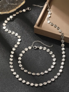 Detailed view of silver sunburst disc necklace and bracelet set on black background