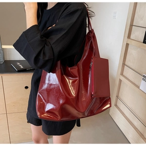 Detail view of large burgundy patent leather tote bag with matching inner pouch on model