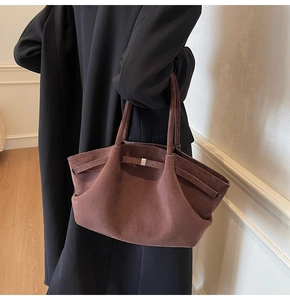 Détail du sac cabas en daim caramel avec design ailé et sangles latérales réglables