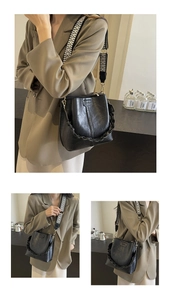 Detail of black PU leather bucket bag with geometric wide strap and chain accent