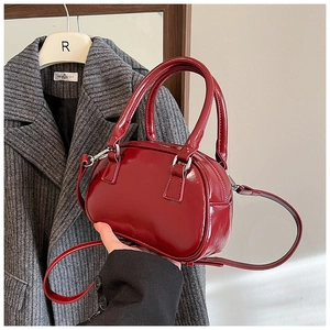 Detailed macro view of bright red patent leather texture and silver hardware on handbag