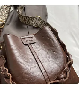 Close-up of deep brown soft leather bucket bag with ethnic textured wide shoulder strap