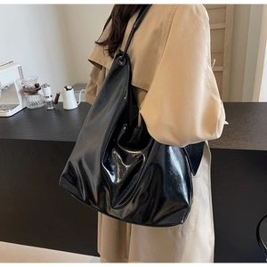 Side view of a black glossy hobo bag with large capacity worn on shoulder in cafe