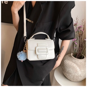 Modella che indossa una borsa a tracolla bianca con fibbia decorativa e pompon azzurro