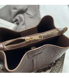 Close-up of smooth gold-tone zipper and textured brown leather on bucket bag