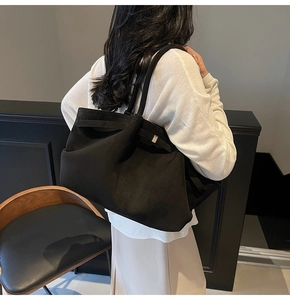 Détail du grand sac cabas minimaliste en daim noir avec boucle métallique sur un mannequin