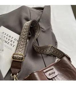 Close-up of adjustable ethnic pattern wide strap and brown leather crossbody bucket bag