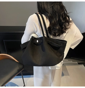 Détail du grand sac cabas noir mat avec boucle argentée porté par un mannequin