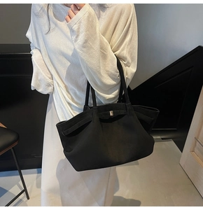 Détail d'un grand sac cabas noir en daim mat avec une boucle décorative élégante