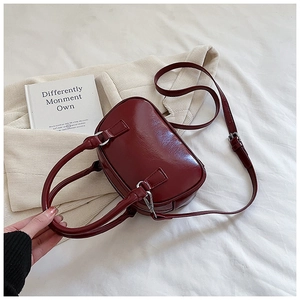 Detail of a dark red glossy bowling bag with silver hardware and adjustable strap