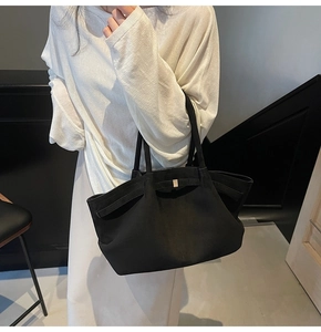 Grand sac cabas noir en daim porté à l'épaule dans un intérieur au style minimaliste