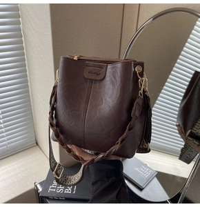 Detail of dark brown bucket bag featuring lychee texture and ethnic style wide strap