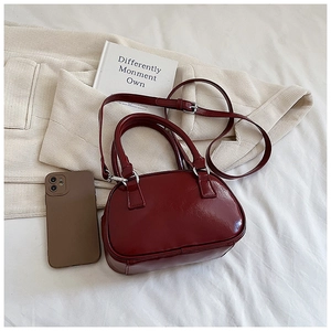 Detail of burgundy patent leather bowling bag with silver hardware and top handle
