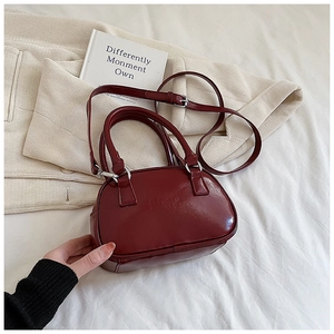 Detail of red-brown glossy faux leather bowling bag with silver metal hardware and straps