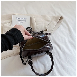 Close-up of brown glossy patent leather handbag interior showing beige lining and pocket