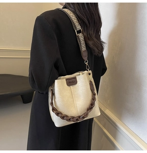 Detail of off-white bucket bag with brown woven handle and houndstooth strap