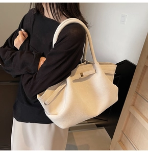 Détail du grand sac cabas en suédine beige avec boucle dorée porté par un modèle