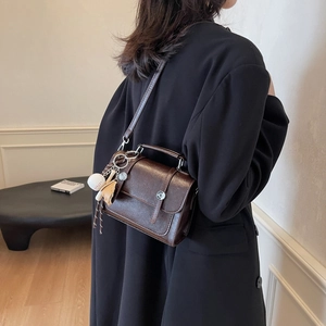 Vintage dark brown crossbody bag with silver buckle and baseball charm shown on a model