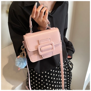 Dettaglio della borsa squadrata rosa chiaro con pompon blu e fibbia decorativa in pelle