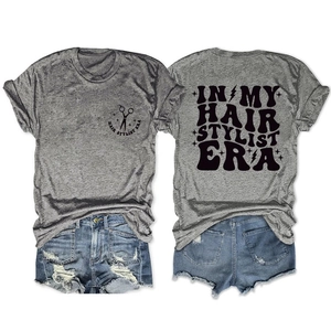 Flat lay of gray cotton t-shirt with Hair Stylist Era text and denim shorts set