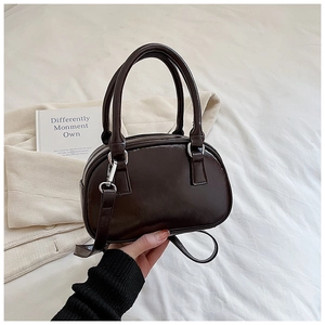 Close-up of a glossy deep brown Boston bag with silver metal buckles and double handles