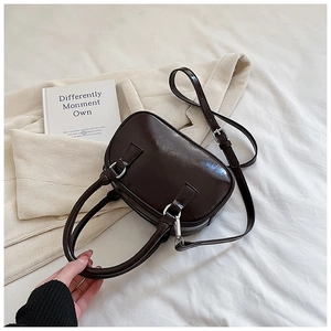 Close-up of deep brown glossy bowling bag with silver hardware on a textured fabric