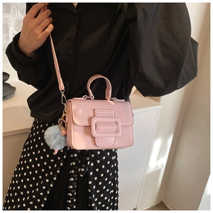Mini borsa quadrata rosa con ciondolo a pompon blu indossata da modella in abito a pois