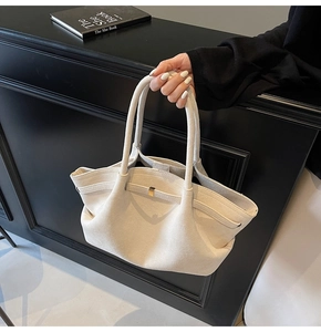 Gros plan sur le sac fourre-tout en daim beige avec boucle en métal et design épuré