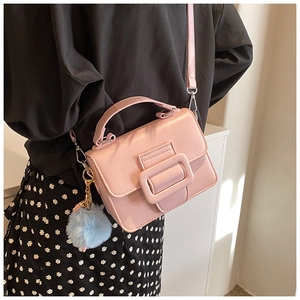 Dettaglio della piccola borsa rosa in pelle PU con manico rigido e ciondolo a pompon