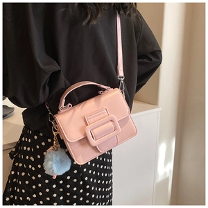 Borsa a tracolla rosa in pelle opaca con ciondolo a pompon blu indossata da una modella