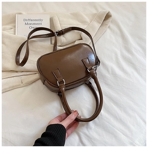 Close-up of a glossy dark brown leather Boston bag with silver hardware and top handles