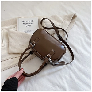 Close-up of a dark brown mini bowling bag with glossy finish and silver hardware details