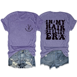 Detail of purple Hair Stylist Era t-shirt featuring scissor print and distressed denim shorts