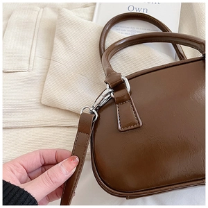 Detailed close-up of brown leather bag showing silver hardware and stitching texture