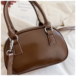 Detailed macro view of the brown oil-wax leather texture and silver metal rings on the bag