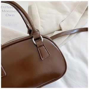 Detail of a brown glossy bowling bag featuring silver D-rings and premium PU leather texture