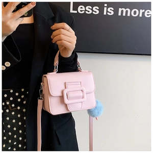 Dettaglio borsa quadrata rosa con tracolla e ciondolo a pompon in peluche blu