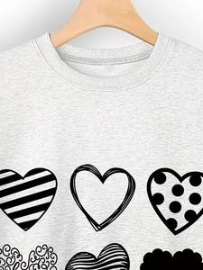 Close-up of light grey crewneck sweatshirt featuring nine unique black heart-shaped prints