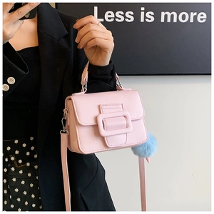 Dettaglio mini borsa rosa a tracolla con fibbia quadrata e charm a pompon azzurro