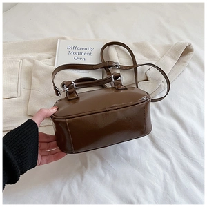 Close-up of a dark brown mini bowling bag featuring glossy PU leather and silver hardware