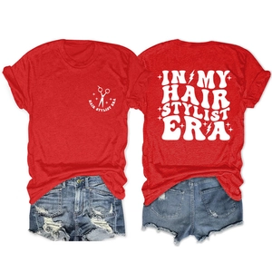 Flat lay of red cotton t-shirt featuring hair stylist era print and blue denim shorts