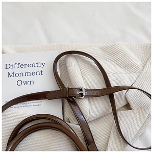 Close-up of adjustable brown leather shoulder strap with a silver square metal buckle