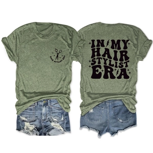 Detailed flat lay of green crew neck T-shirt with black hair stylist graphic and denim shorts