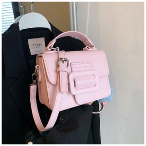 Dettaglio di una borsa in pelle rosa chiaro con grande fibbia decorativa e tracolla rimovibile