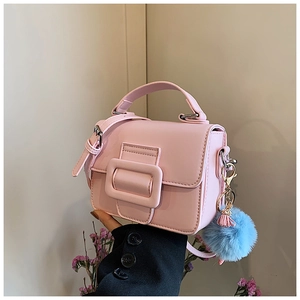 Dettaglio mini borsa quadrata in ecopelle rosa con pompon blu e fibbia decorativa